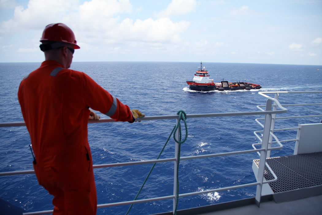 worker on a marine operation and a survey boat in background